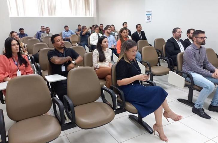 Fotografia em ambiente fechado de dezenas de pessoas sentadas lado a lado.