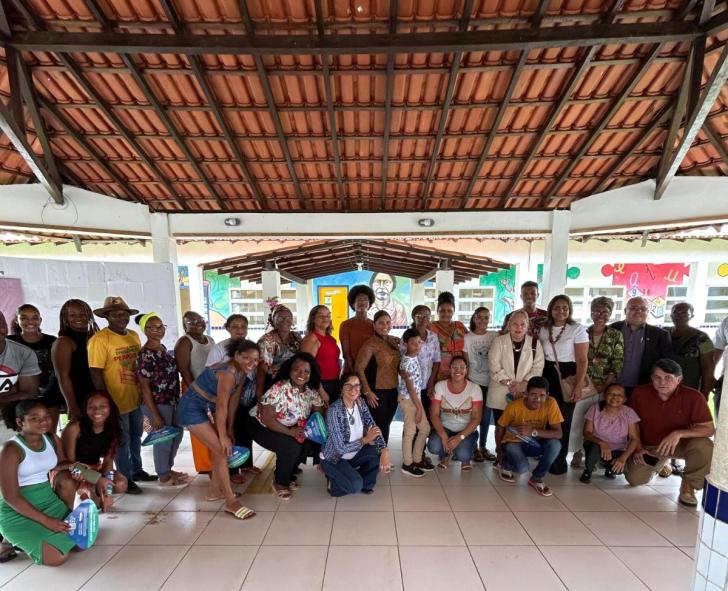 Foto colorida de um grande grupo de moradores de curiaú junto a magistrados do TRT8 em visita a uma escola local.