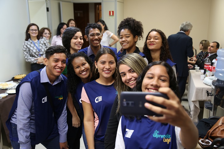 9 pessoas em pé segurando um telefone celular fazendo uma selfie com os coletes azuis.